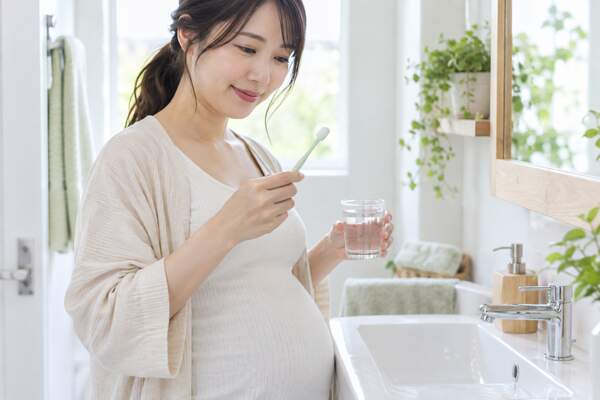 小さな歯ブラシと水を用意してお口ケアをする妊婦さん