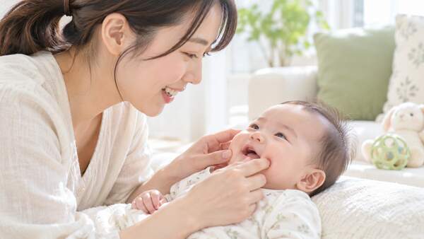 保護者が赤ちゃんの頬や口元にやさしく触れる様子