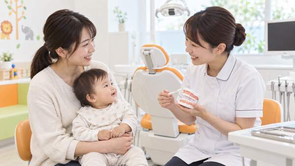 保護者と赤ちゃんが女性歯科医師から歯みがきの説明を受ける様子