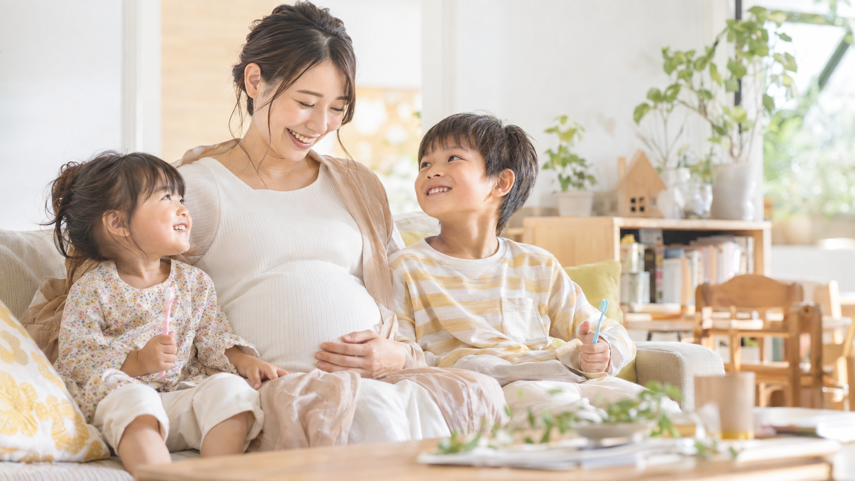 妊娠中のお母さんと幼児・小学生の子どもが一緒にお口の成長を見守る写真