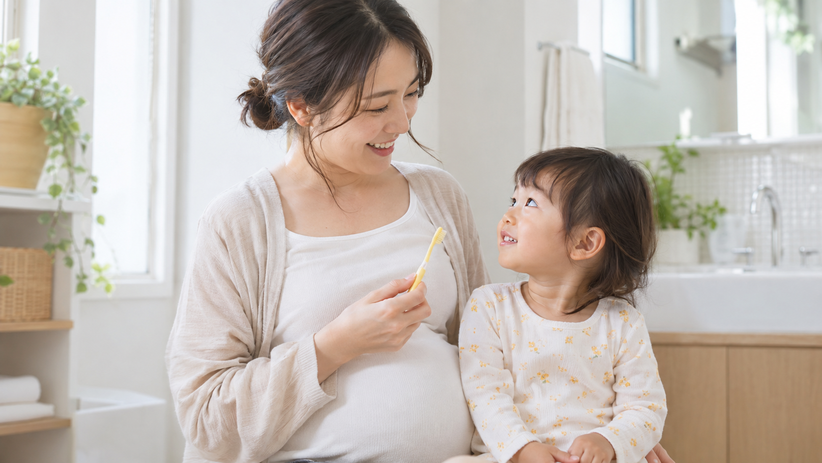 妊娠中のお母さんが幼児と歯ブラシを見ながらお口ケアを始める写真
